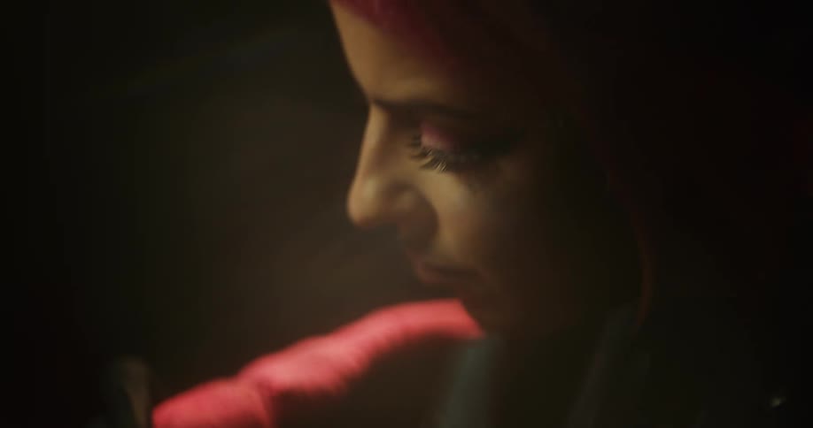 Close up of a tattoo artist with colorful hair working on the skin of a client