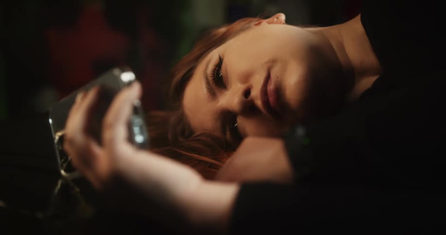 Young woman resting on a couch leisurely browsing her smartphone