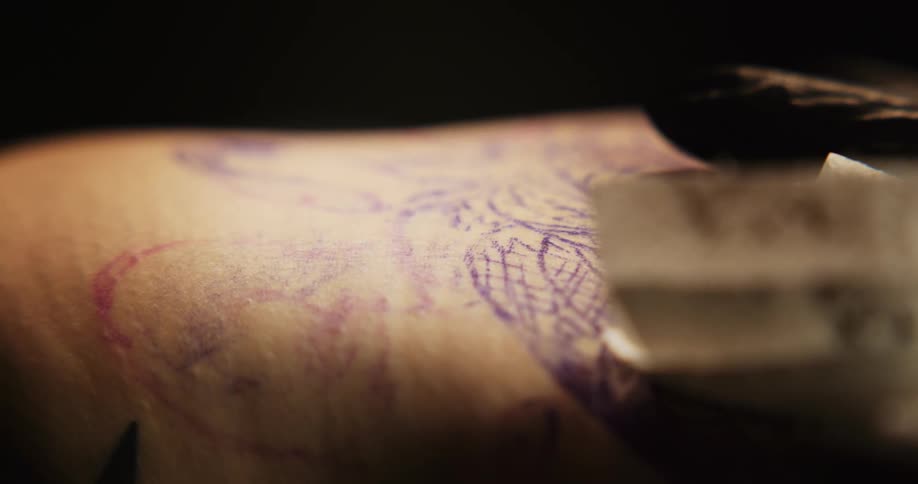 A gloved hand tattoos skin and moves a papertowel