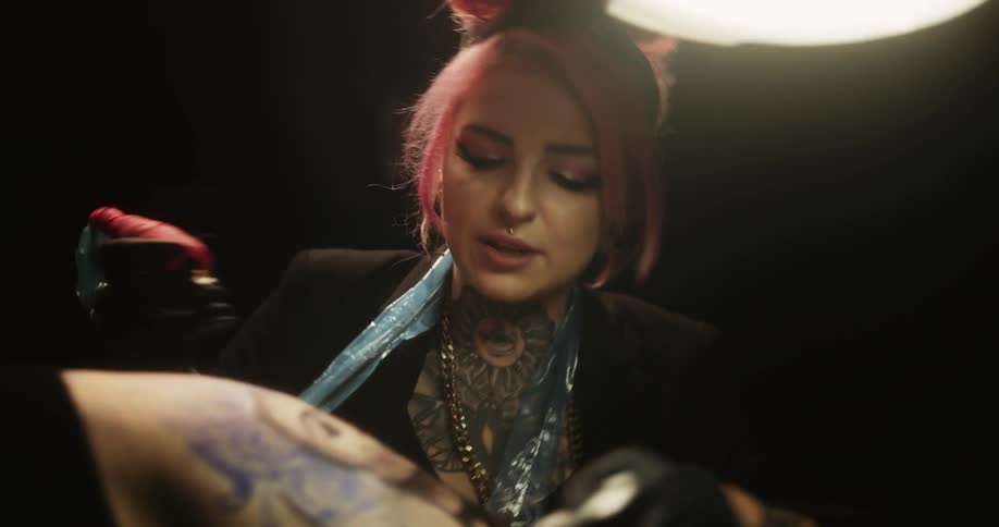 A tattoo artist works on a mans upper arm