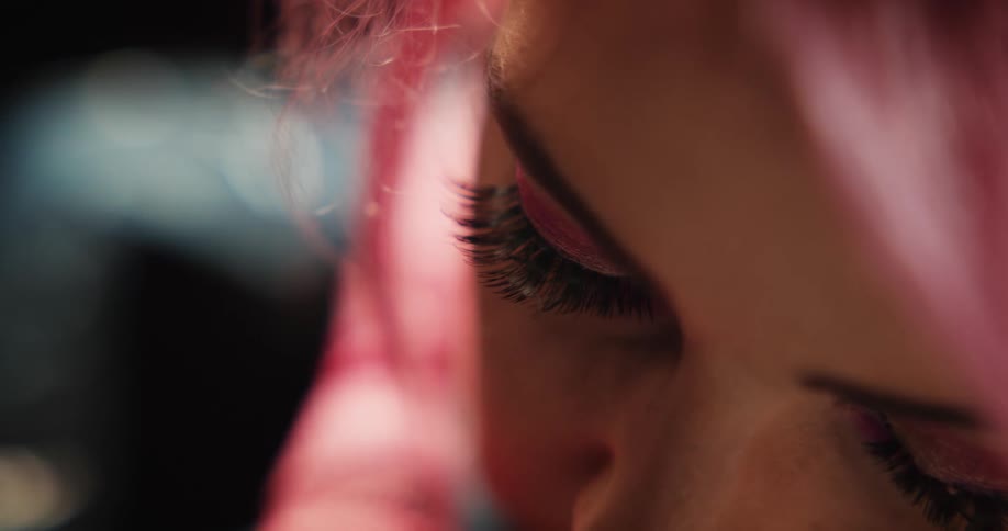 Close up of a tattoo artist with colorful hair working on the skin of a client