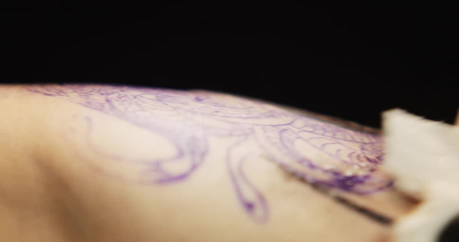 Close up of a tattoo artist cleaning the skin of a customer after a tattooing session