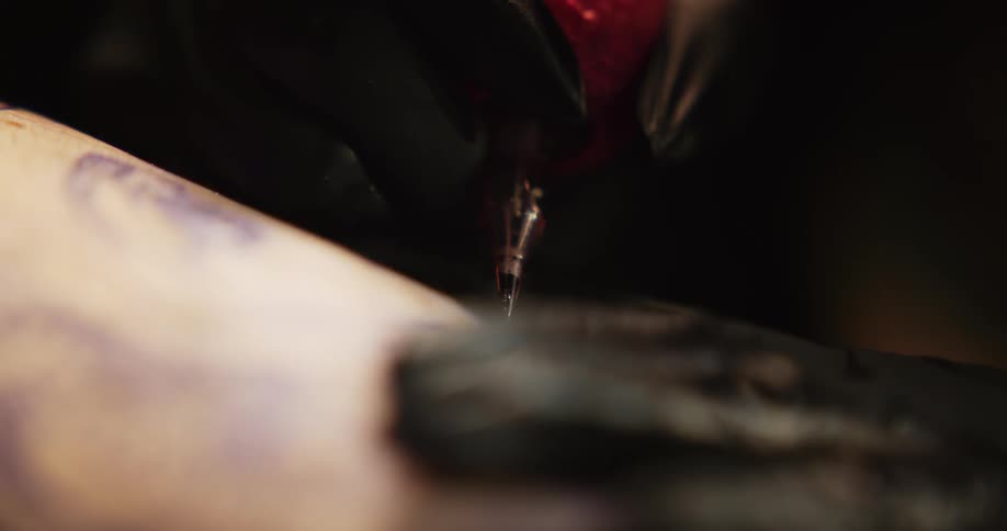 Close up of an artists using a tattoo machine on the skin of a customer