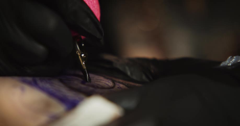 Tattooist works on tattoo wiping skin after applying ink