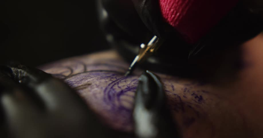 A tattoo artist applies ink to a customer with a needle and then blots it with a cloth