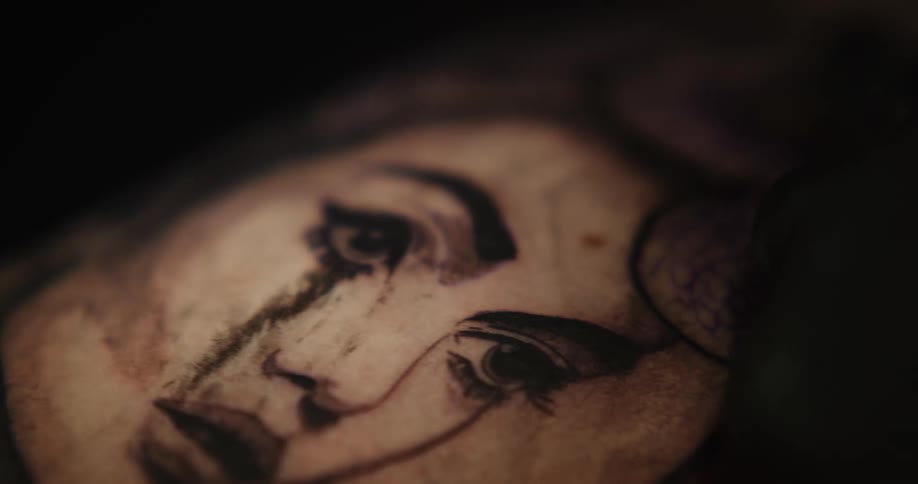 Close up of an artists using a tattoo machine on the skin of a customer