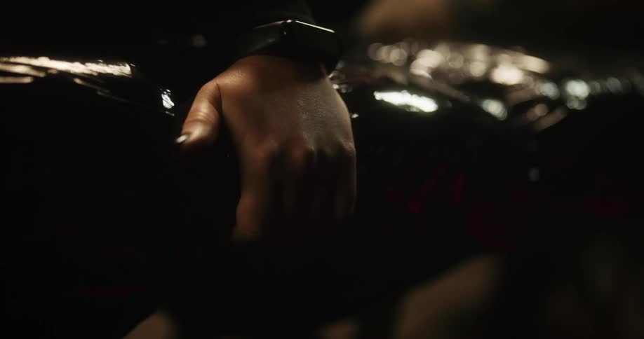 Close up of the hand of a woman with black nails grasping black latex