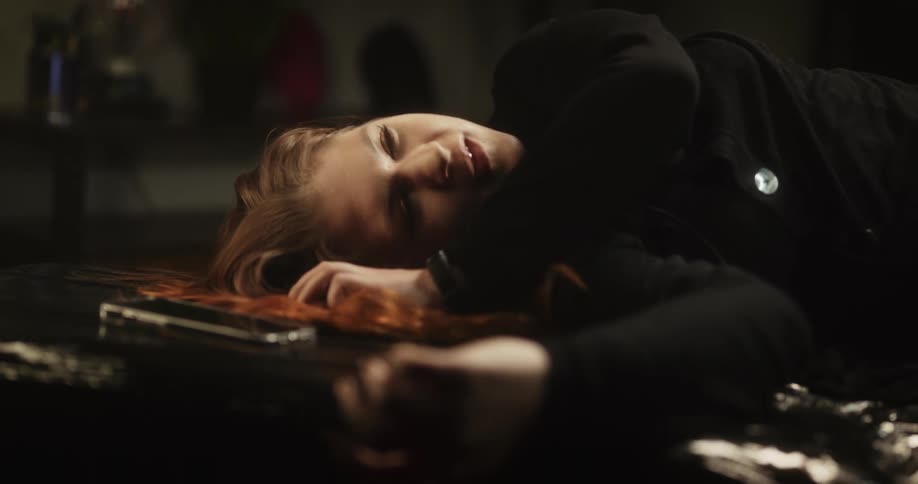 A woman lies down on the ground next to her phone