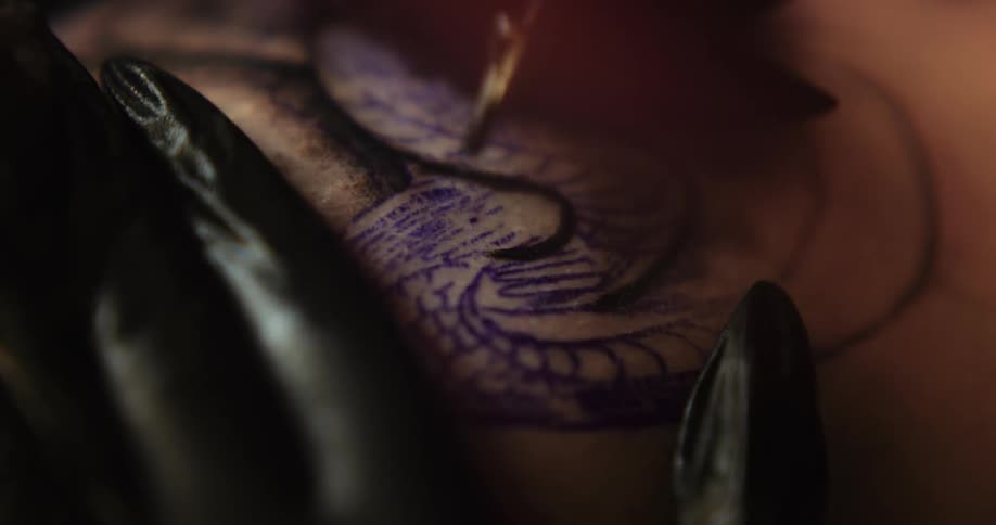 Close up of a tattoo artist using a tattooing machine to work on the skin of a client