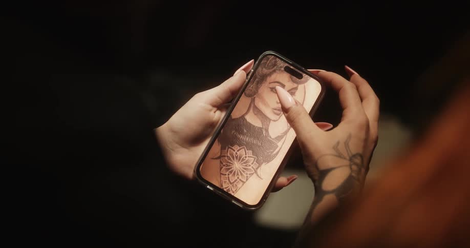 Tattoo artist looks at a picture of her work on a smartphone