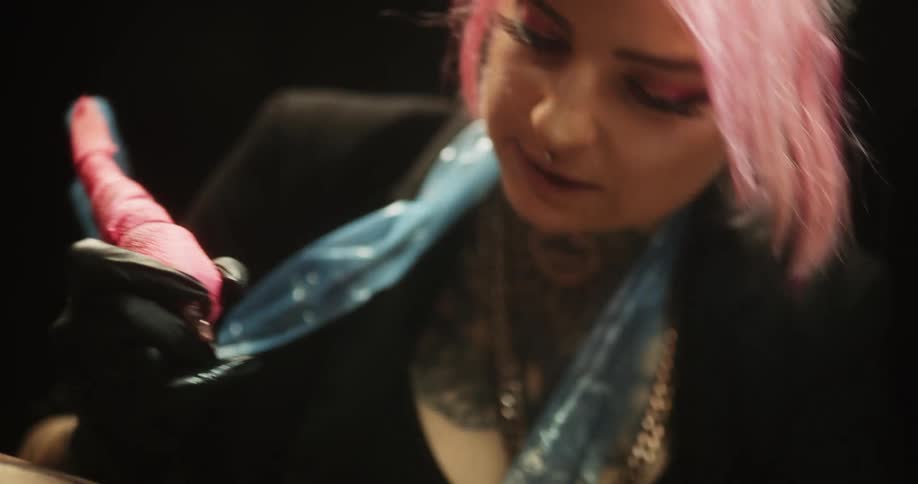 A woman is giving someone else a tattoo at a tattoo shop
