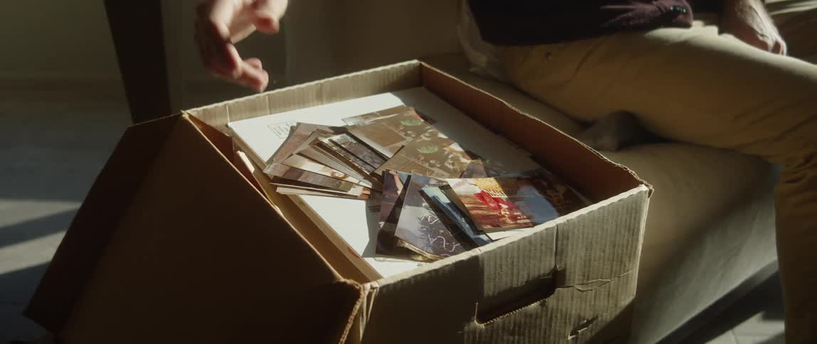 A man sits down to go through a box of photographs