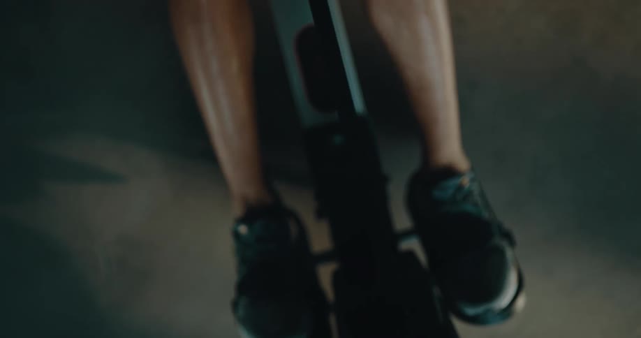 Top down view of a strong muscular man sweating while working out on a rowing machine