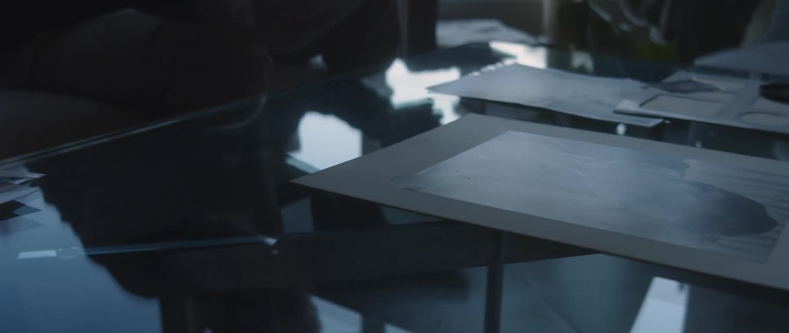 Reflected silhouette of a person selecting sketches printed on cardboard on the office