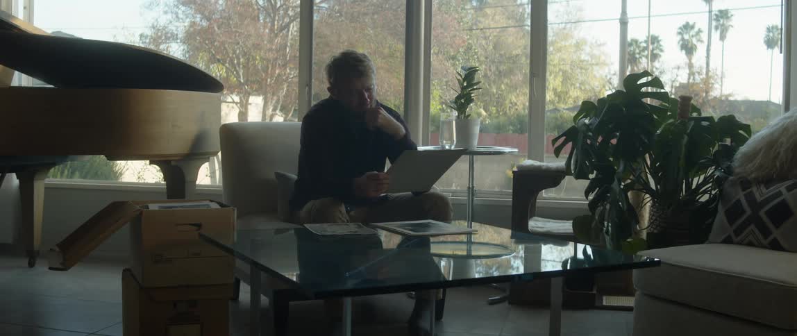 There is a young man that is sitting inside of his home