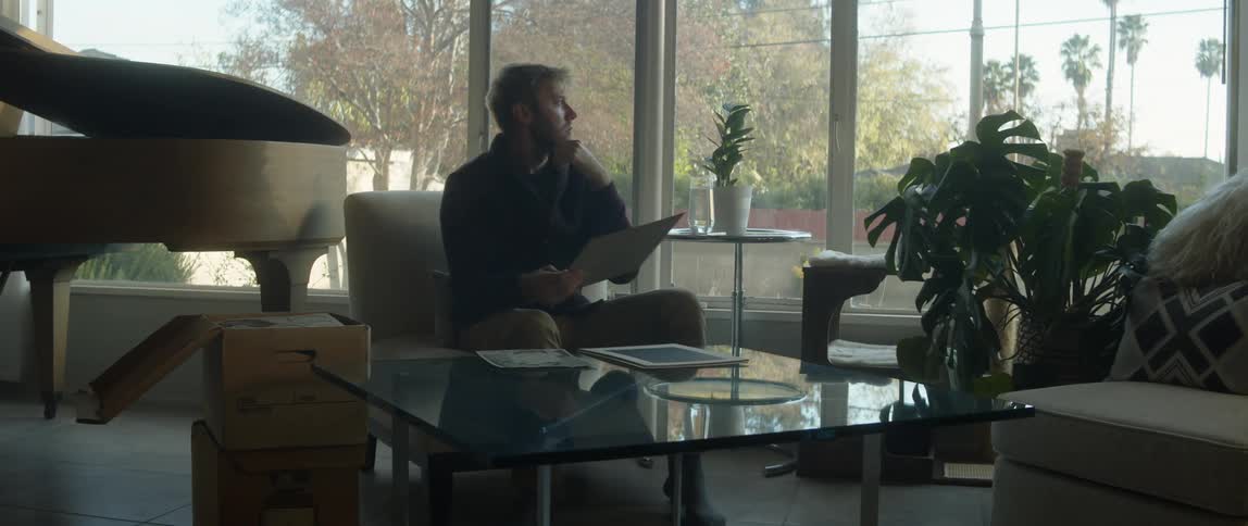 A man is sitting in his living room looking at a photograph
