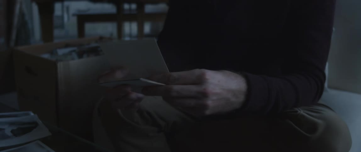Man handling old photographs found on a cardboard box at home