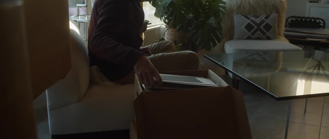 Man handling old photographs found on a cardboard box at home