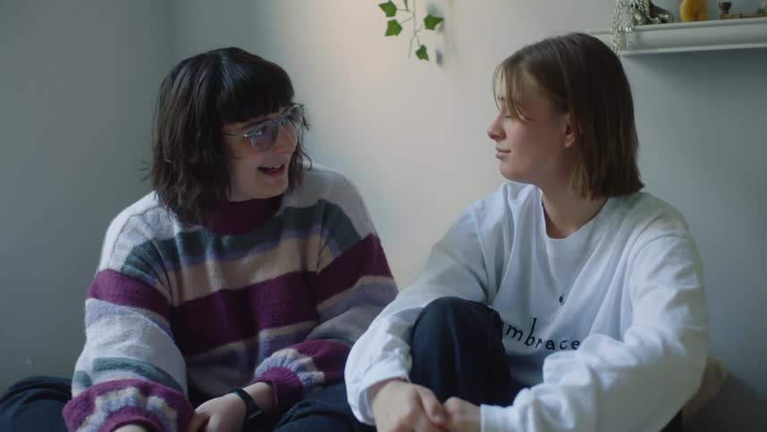 Two teenage girls are sitting together talking and relaxing