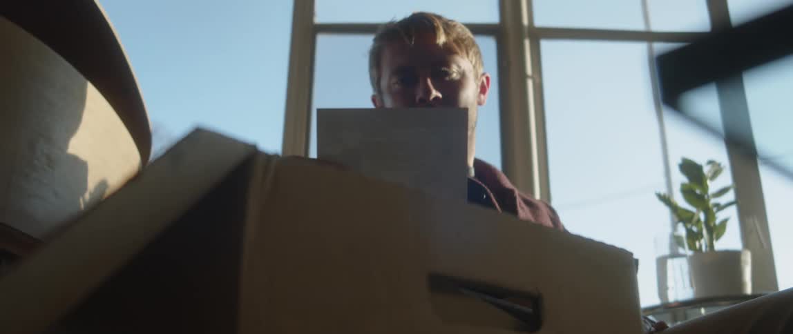 Man handling old photographs found on a cardboard box at home