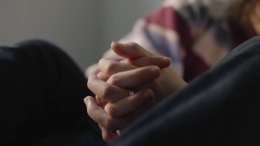 Young couple sitting on a room at home holding hands