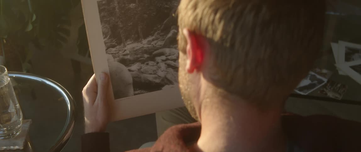 Man handling old photographs found on a cardboard box at home