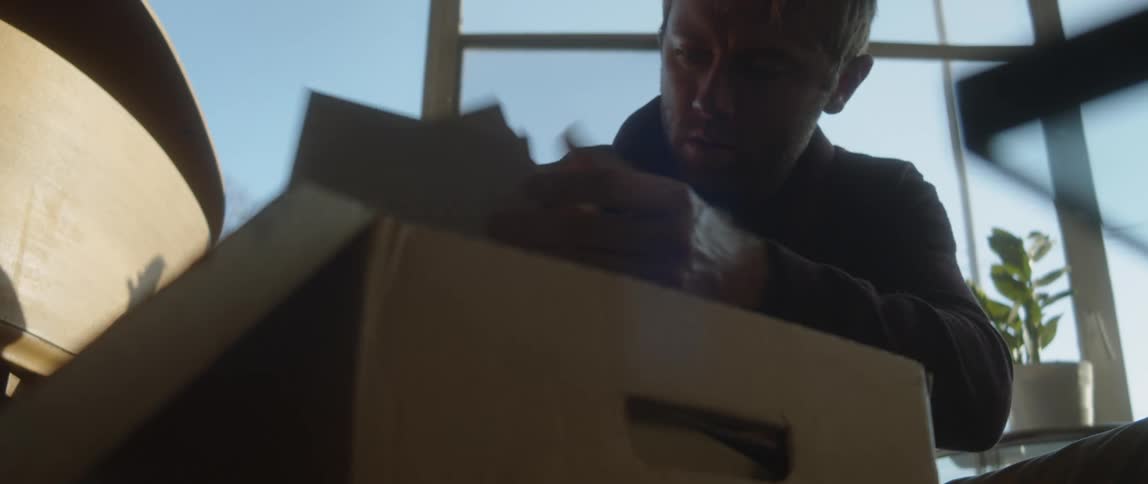 Man handling old photographs found on a cardboard box at home