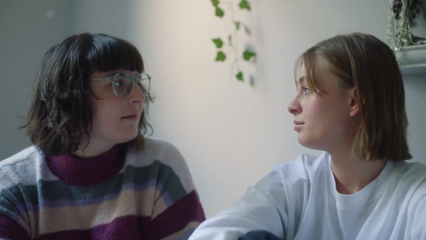 Two teenage girls are sitting together talking and relaxing