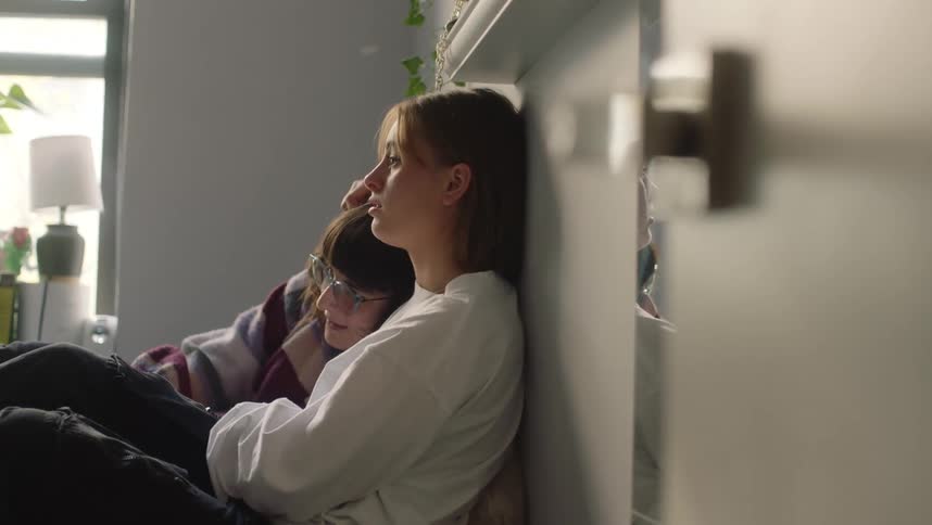 Young couple sitting together over a bed cuddle comfortingly in the bedroom