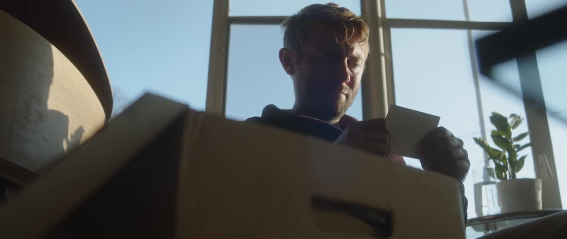 A man takes a photo out of a box and looks at it
