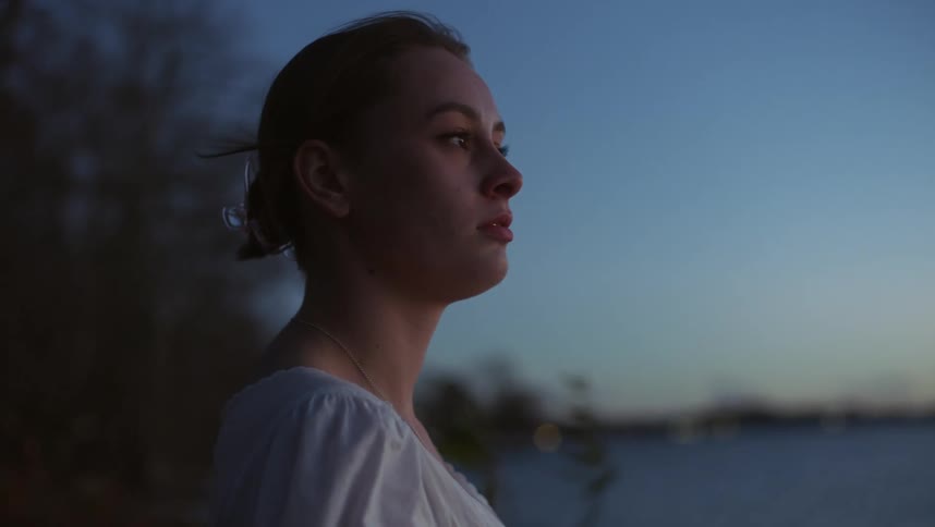 Close up of the face of a young woman looking at the horizon at evening