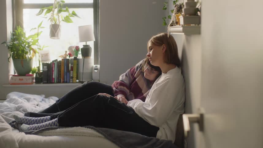 Young couple sitting together over a bed cuddle comfortingly in the bedroom