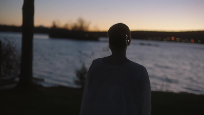 A woman is walking towards the lake