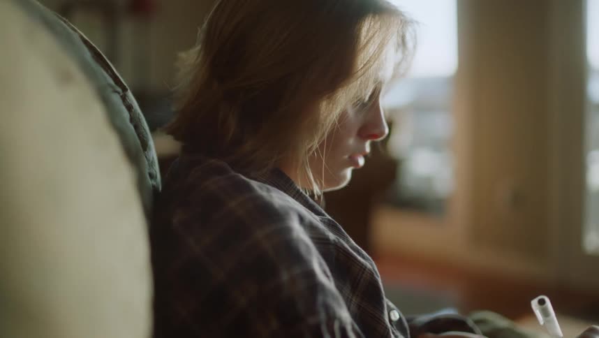 A teenage girl sits at home and writes in a notebook