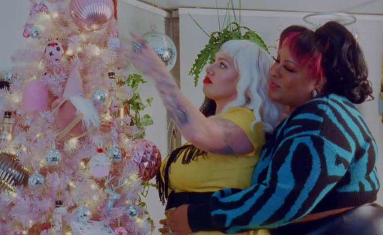 A young happy couple decorating a colorful christmas tree at home