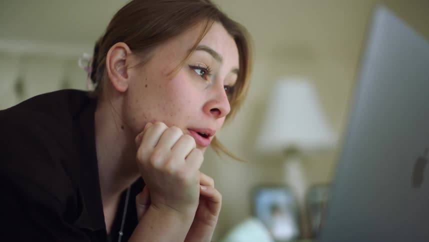 Close up of the face of a young woman talking on a video call through a laptop
