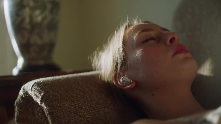 A woman wearing headphones while relaxing on a sofa indoors