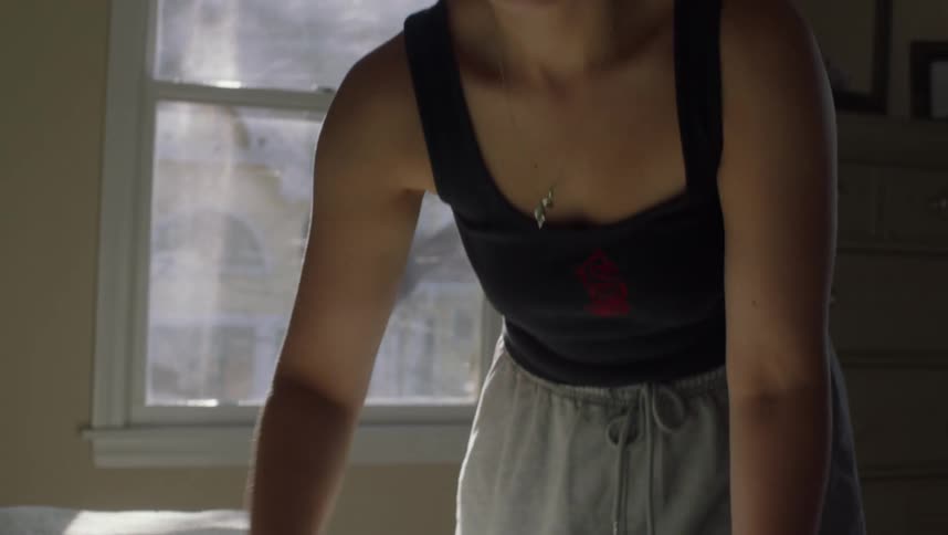 A woman is standing in the bedroom making the bed and rubbing her hand over the blanket