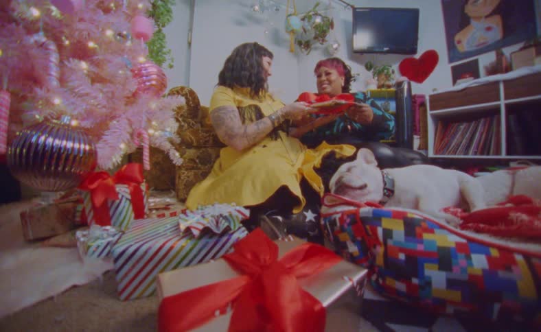Young happy couple open presents near a colorful pink christmas tree