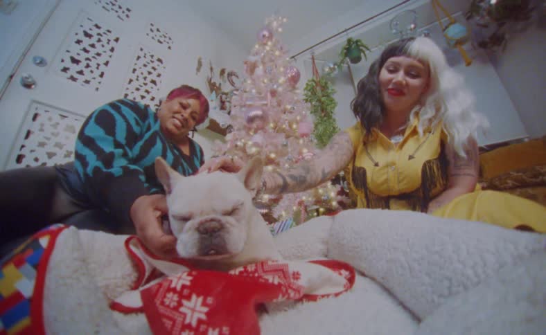 Young happy couple sitting next to a colorful christmas tree with their dog