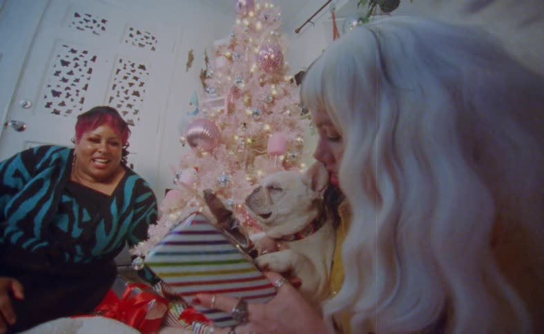 Young happy couple sitting next to a colorful christmas tree with their dog