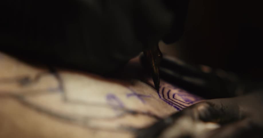 Tattoo artist injects ink and pigments underneath the skin with a small sanitized needle