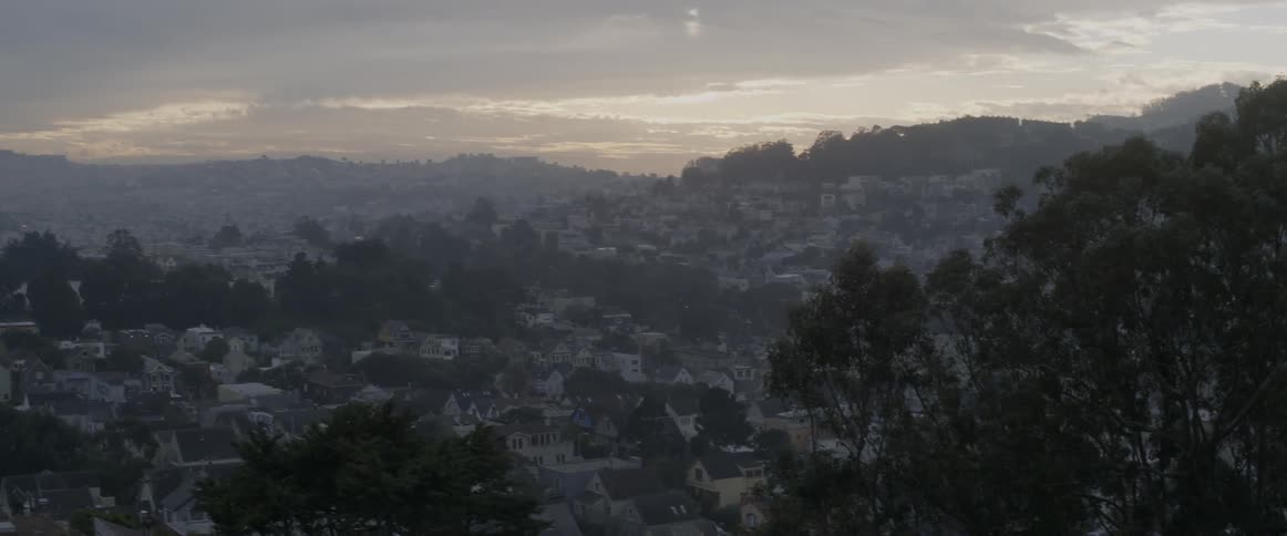 The town below is on hills at sunset