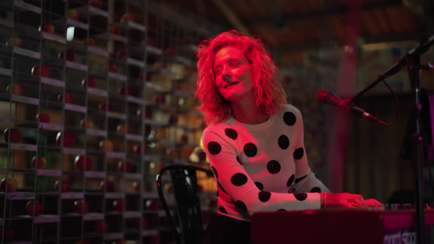 Female singer playing a keyboard performs on stage on a small venue