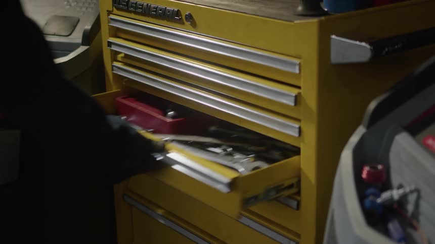 A mechanic removes a wrench from a toolbox