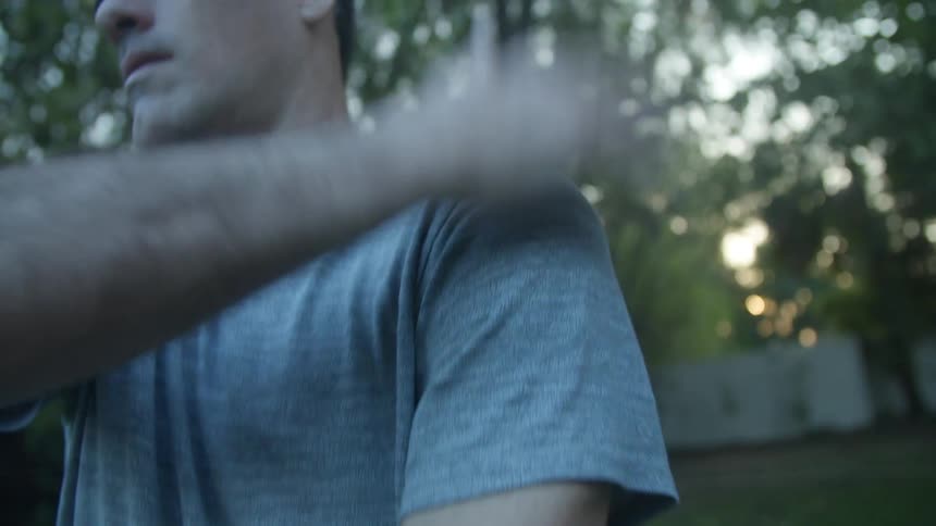 A man smacks his hand up and down his arm