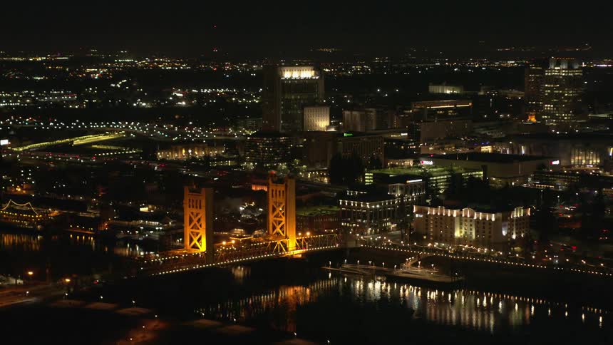 Aerial view of an illuminated suspension bridge over a river in the city at night