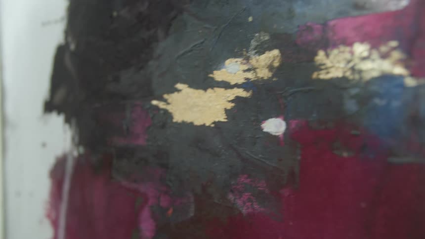 An up close of a abstract painting with gold being brushed on