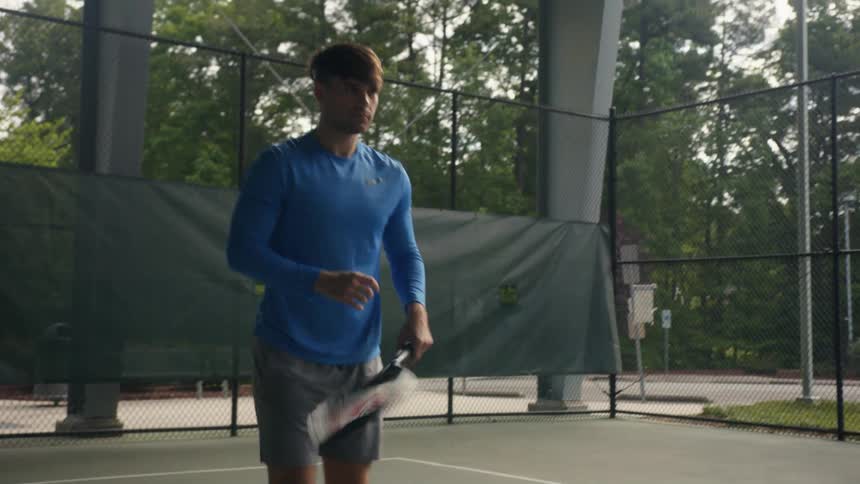 A man on a tennis court swings his racket and jumps up and down as he prepares to play