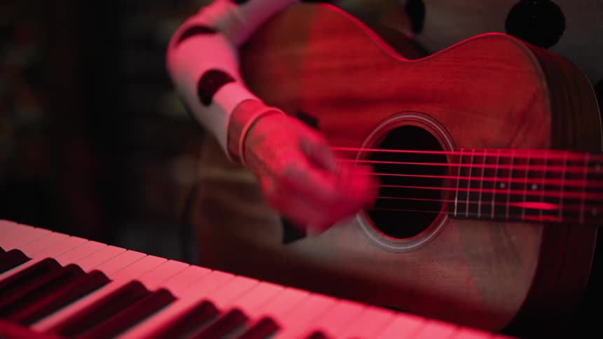 An adult is sitting down and playing acoustic guitar